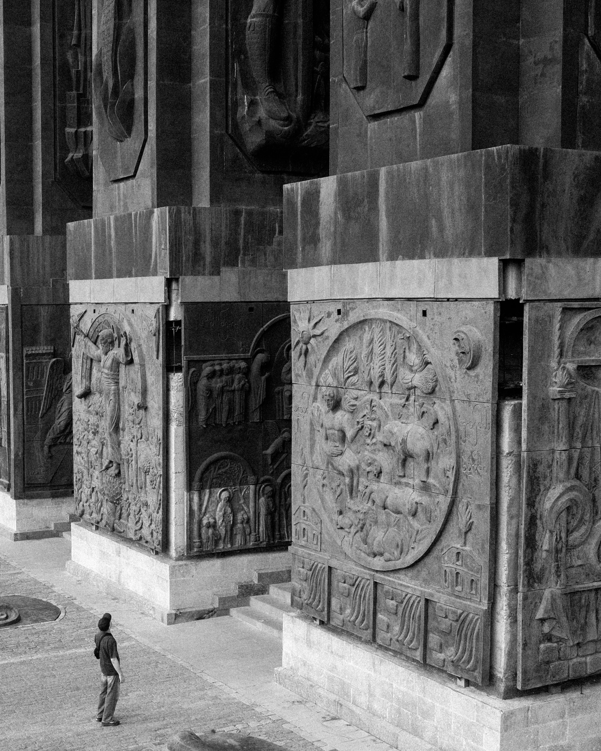 A lone visitor looking up at monumental carved stone columns