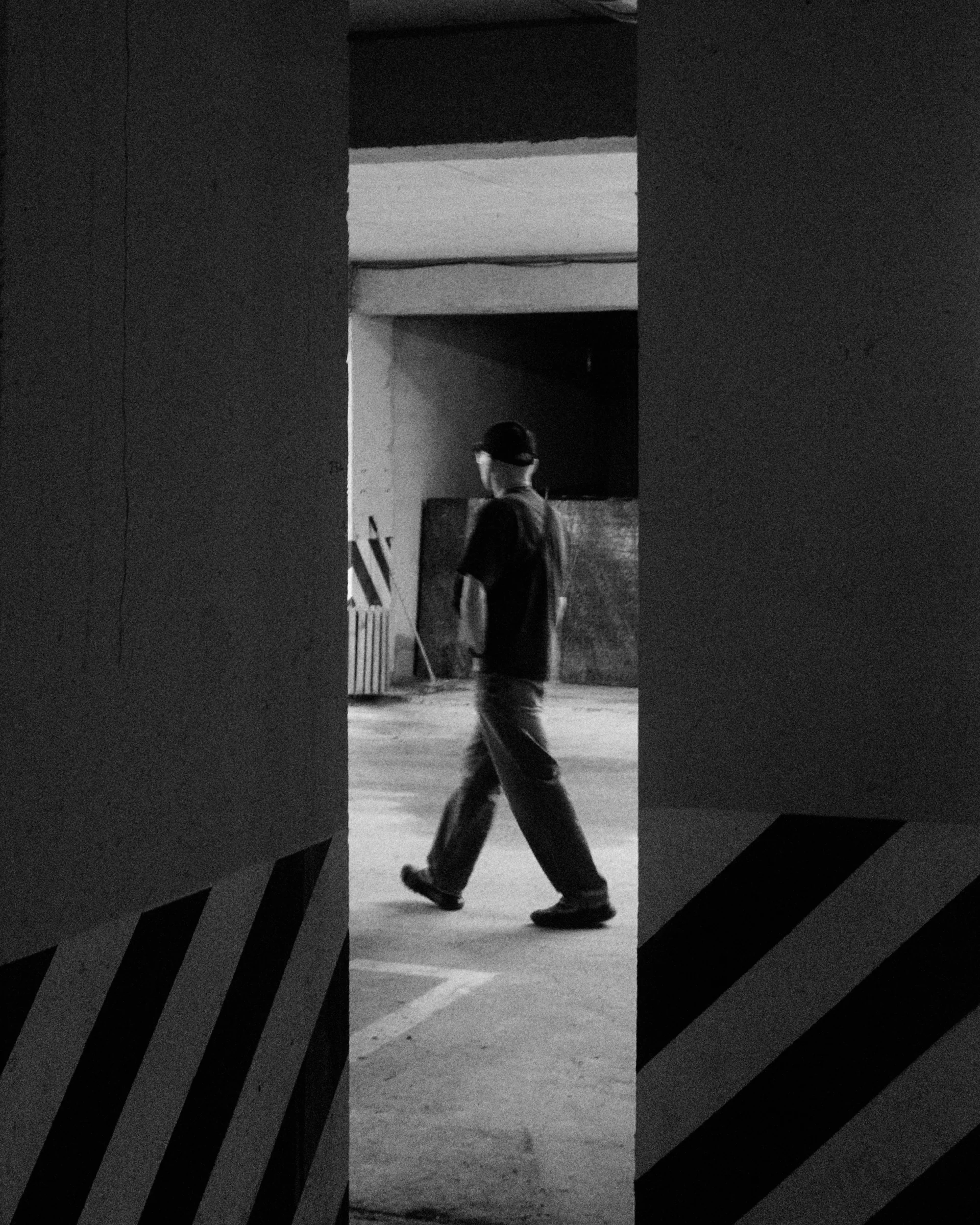 A person walking between concrete columns with diagonal stripes