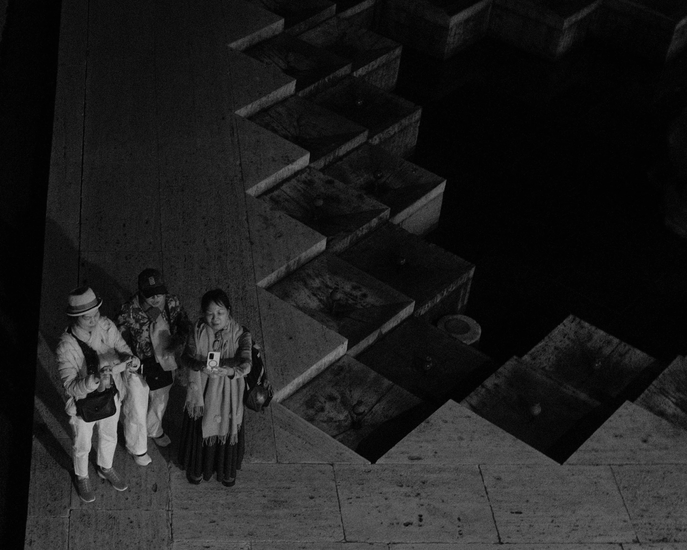 Three visitors beside a zigzag of stone steps, seen from above