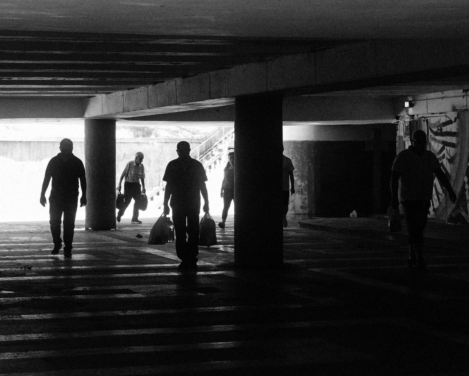 Pedestrians silhouetted against the entrance to an underpass